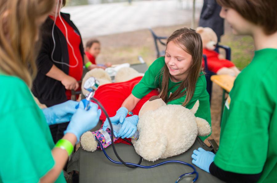 Kinder üben Erste Hilfe an einem verletzten Teddybären