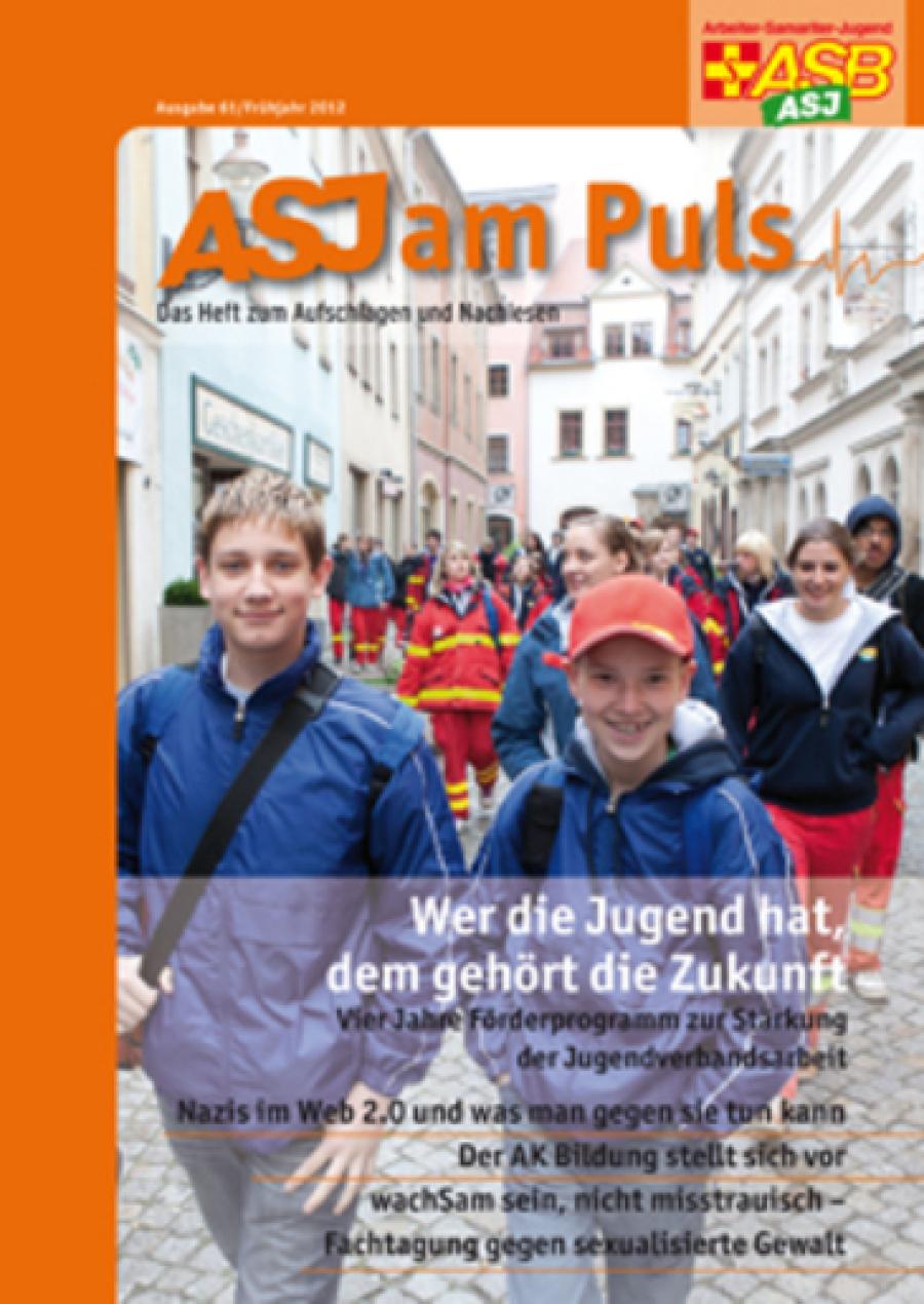 Titelseite des ASJ am Puls. Eine große Gruppe ASJlerinnen und ASJler läuft durch eine Stadt.